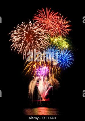 Stunning fireworks display with happy colors on black night sky background, reflected on water Stock Photo