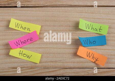 Questions - Why? What? Where? When? Why? How? on colorful stickers on wooden desk Stock Photo