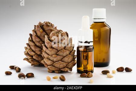 two pine cones with pine nuts and glass bottles on a white background, close-up Stock Photo