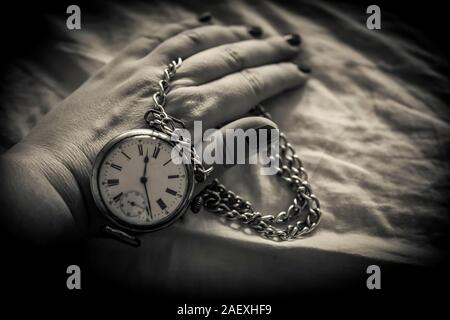 A black and white photo of a woman's hand holding a retro pocket watch Stock Photo