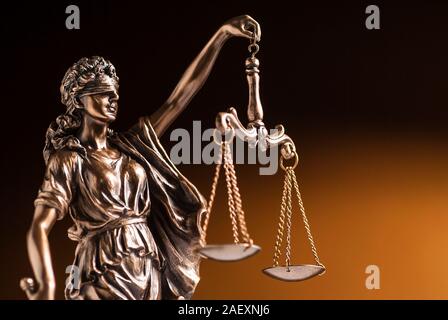 A blindfolded bronze statue of Justice on a brown background  Stock Photo