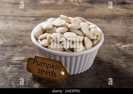 Pumpkin seeds in white bowl on wooden background. Stock Photo