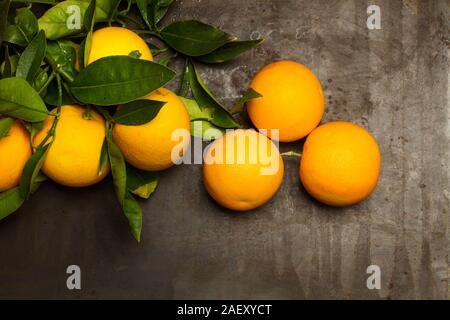 Oranges and orange leaves leaves on a rusty metal table in a top view Stock Photo