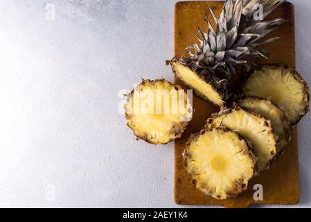 Pineapple on wood texture background. Whole and sliced tropical pineapple on a wooden board. Top view with place for your text.