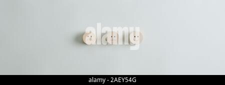 Wooden cut circles with faces representing positive, negative and neutral grade placed in a row over grey background. Wide view image with copy space. Stock Photo