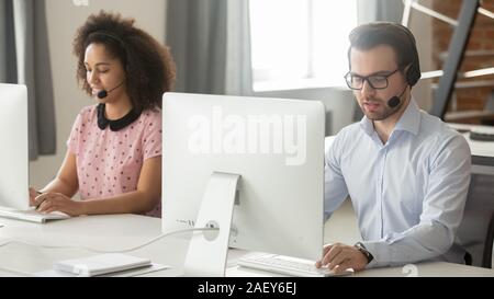 Diverse operators in headphones work on pc consulting clients Stock Photo