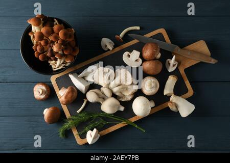 Different mushrooms, knife, dill, board and bowl on wooden background, top view Stock Photo