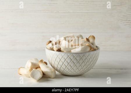 Fresh eringi mushrooms in bowl on white wood background, space for text Stock Photo