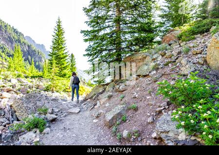 Maroon Bells trail view in Aspen, Colorado with woman backpack hiker walking in July 2019 summer on path road view Stock Photo