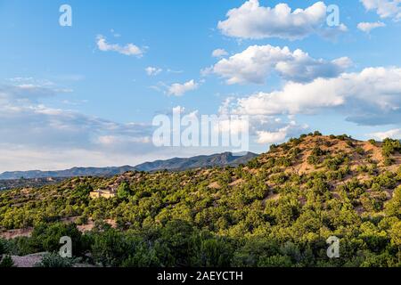 Sunset in Santa Fe, New Mexico Tesuque community neighborhood with houses green plants pignon trees shrubs and blue sky clouds Stock Photo