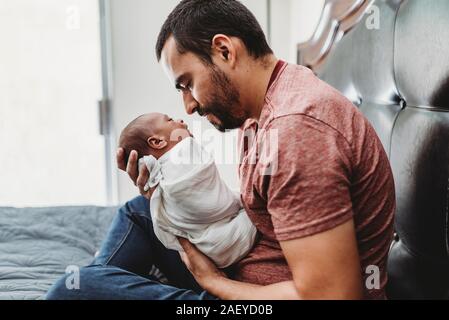 Mid-30â€™s dad with beard admiring newborn wrapped in white blanket Stock Photo