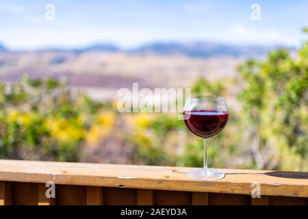 Red wine glass on terrace railing and bokeh background view of autumn foliage yellow trees in Aspen, Colorado rocky mountains Stock Photo