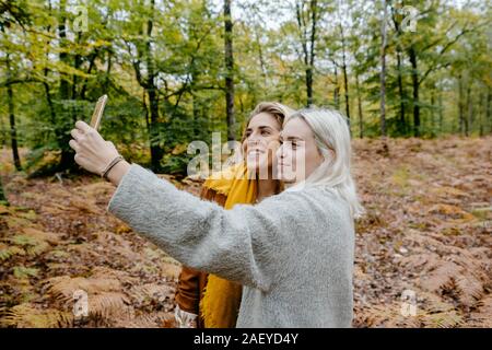 Two blondie women taking a selfie in a autumnal forest Stock Photo