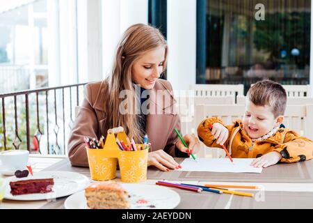 mother and son in the restaurant painted pencils before eating Stock Photo