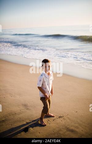 Young Boy Standing on Beach at Sunset Stock Photo