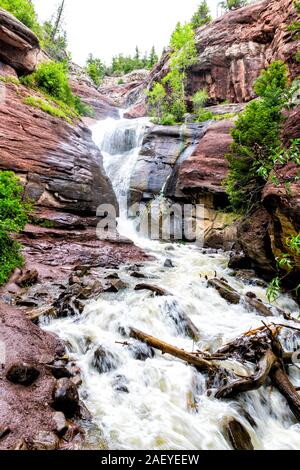 Hays creek falls waterfall in Redstone, Colorado during summer with raging river water from snowmelt flood and red rocks long exposure Stock Photo