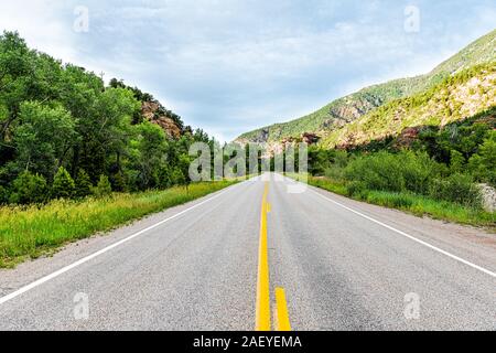 Rocky red mountains road Highway 133 in Redstone, Colorado during summer with trees in evening sunlight and cars wide angle view perspective Stock Photo
