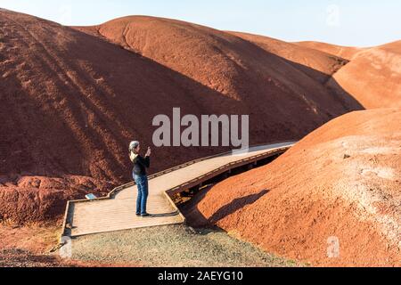 A young woman takes pictures with her smartphone on Paint Cove Trail in Painted Hills Stock Photo