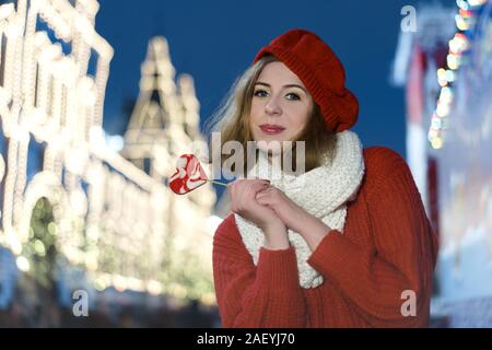 Cheerful young girl with caramel candy in the shape of a heart in her hand Stock Photo