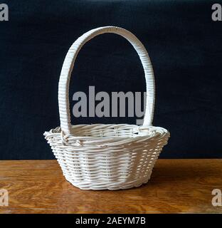 Blanching basket braided from twig on dark background cost(stand)s on wooden table Stock Photo