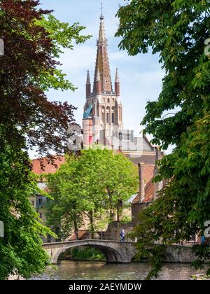 Wijngaard bridge over canal and tower of Church of our Lady, Onze-Lieve-Vrouwekerk, in Bruges, West Flanders, Belgium Stock Photo