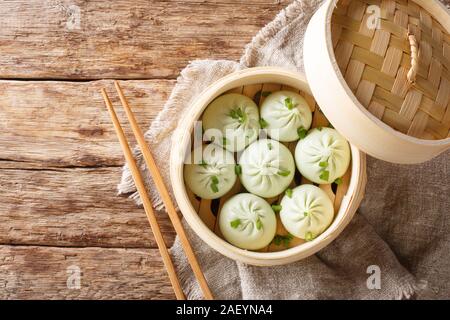 Bamboo steamer with tasty baozi dumplings closeup on table. Horizontal top view from above Stock Photo
