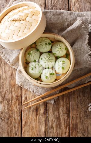 Steamed baozi chinese buns in bamboo steamer closeup on the table. Vertical top view from above Stock Photo