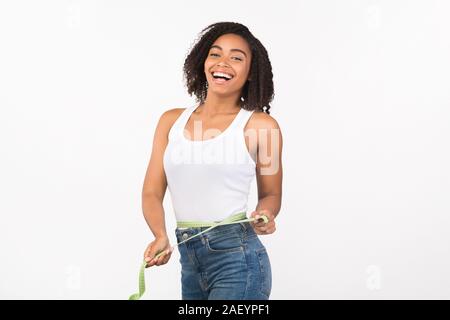 Perfect Body. Happy african american woman holding measuring tape around her waist and looking at camera. Copy space Stock Photo