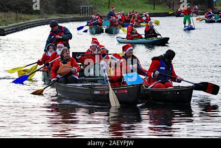 A young girl Santa is mast head on this canoe splashing along the Leeds and Liverpool canal in Liverpool, Santa Splash Bootle 2 7.12.19 Stock Photo