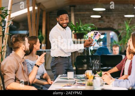 Creative designers discussing work, choosing colors for new project, having meeting in office Stock Photo