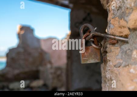 Rusty padlock with unfocused background. In a ruined shed in the cove of Ses Covetes, Majorca Stock Photo