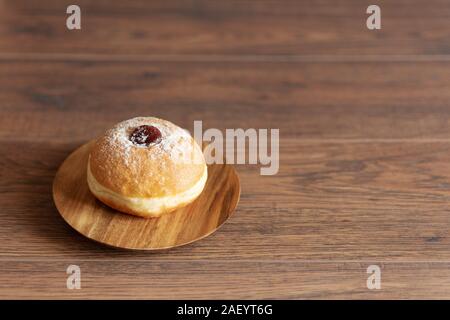 Hanukkah sufganiyot. Traditional Jewish donuts for Hanukkah with red jam and sugar powder. Copy space. Stock Photo