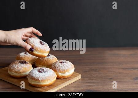 Hanukkah sufganiyot. Traditional Jewish donuts for Hanukkah with red jam and sugar powder. Copy space. Stock Photo