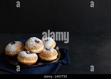 Hanukkah sufganiyot. Traditional Jewish donuts for Hanukkah with red jam and sugar powder. Copy space. Stock Photo