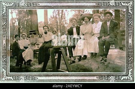 Vintage photograph of 8 people in a park sitting on a see-saw, circa 1915 with a crowd looking on. Stock Photo