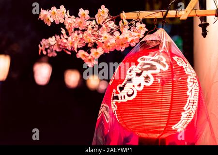 Kyoto, Japan - April 9, 2019: Alley colorful street in Gion district at night with closeup of illuminated red paper lantern covered in plastic for rai Stock Photo