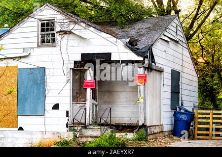 Atlanta, USA - April 21, 2018: Old abandoned weathered white wooden house with entrance and notice signs warning from fire marshal Stock Photo