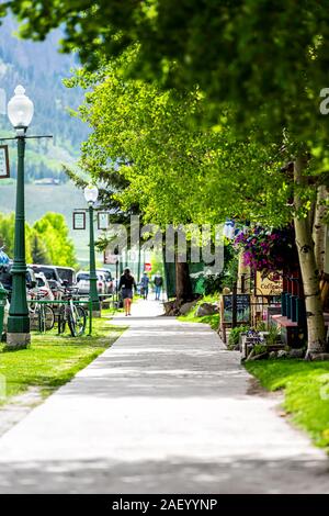 Crested Butte, USA - June 21, 2019: Colorado village downtown in summer with sidewalk path on elk avenue by green trees on sunny day Stock Photo