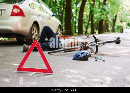 Victim on the asphalt. Bicycle and silver colored car accident on the road at forest at daytime Stock Photo