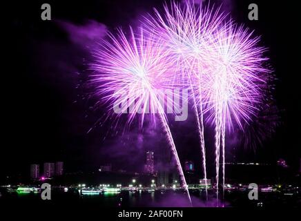 Vibrant pink and purple fireworks splashing in the night sky over the city Stock Photo