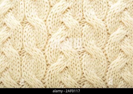 Beige knitted fabric wool texture for background. Close up of White Knitted material pattern for design. Beige warm sweater textile background. Stock Photo