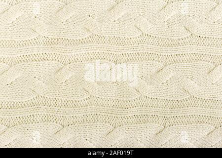 Beige knitted fabric wool texture for background. Close up of White Knitted material pattern for design. Beige warm sweater textile background. Stock Photo