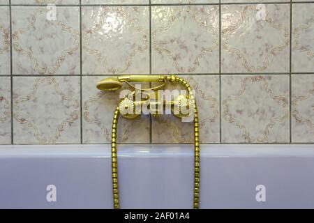 Vintage gold bathtub faucet and ceramic tiles in background.Retro bronze look. antique design Stock Photo