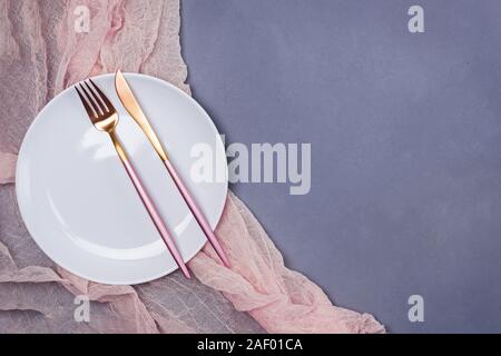 Empty white plate and modern design cutlery on the gray stone table, top view Stock Photo