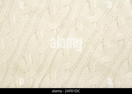 Beige knitted fabric wool texture for background. Close up of White Knitted material pattern for design. Beige warm sweater textile background. Stock Photo