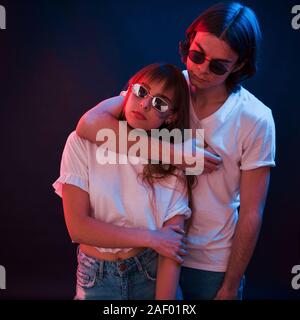 Lovely people. Couple standing in dark room with red and blue neon lighting Stock Photo