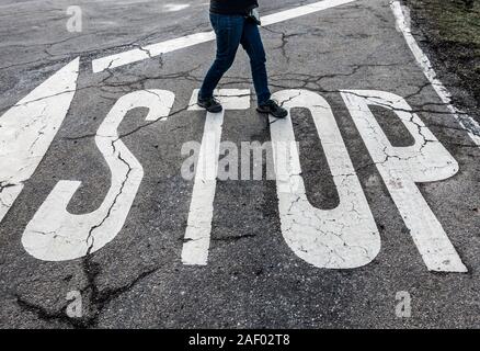 Woman walking over Stop road marking. Stock Photo