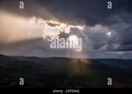 Agricultural landscape, sun beams shining through dark thunderstorm clouds Stock Photo