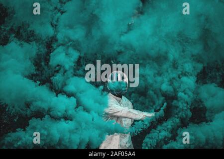 guy in mask standing in between blue smoke bombs Stock Photo