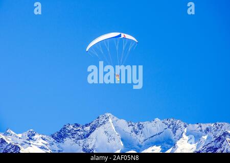 Skiing and paragliding in Austrian Alps.  Unrecognizable skier and paraglider flying over Zillertal Alps near Tux glacier and Hintertux ski resort Stock Photo
